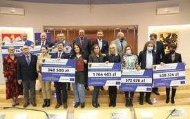 Przedstawiciele samorząd&oacute;w z tablicami prezentującymi kwoty dofinansowania projekt&oacute;w