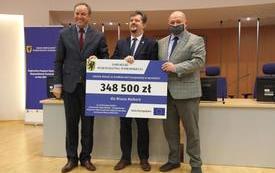 Marszałkowie wojew&oacute;dztwa pomorskiego oraz Burmistrz Malborka trzymają tablicę z kwotą dofinansowania
