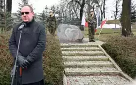przemawiający ksiądz na tle pomnika