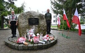 Obelisk ZHP z kwiatami, po obu stronach harcerz