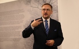 osoba opowiadająca o wystawie na tle jednej z plansz ekspozycyjnych