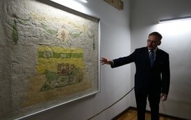 osoba prezentuje mural ze stalagu