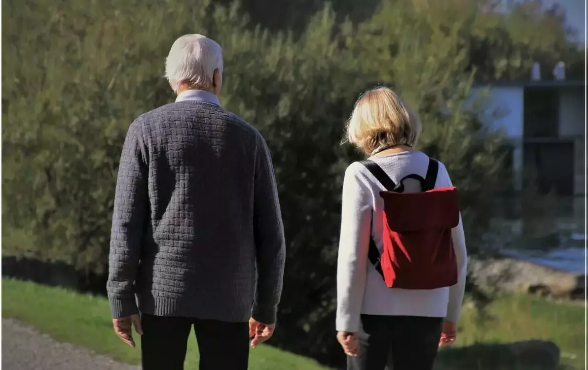 seniorzy na spacerze, mężczyzna i kobieta z plecakiem