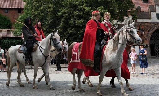 rekonstruktorzy na koniach na tle Muzeum Zamkowego w Malborku