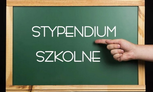 ręka wskazująca na tablicę szkolną z napisem stypendium szkolne